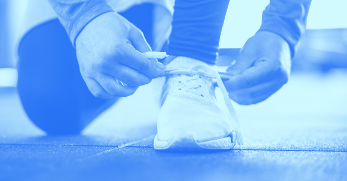 Kneeling down and tying running shoe laces.